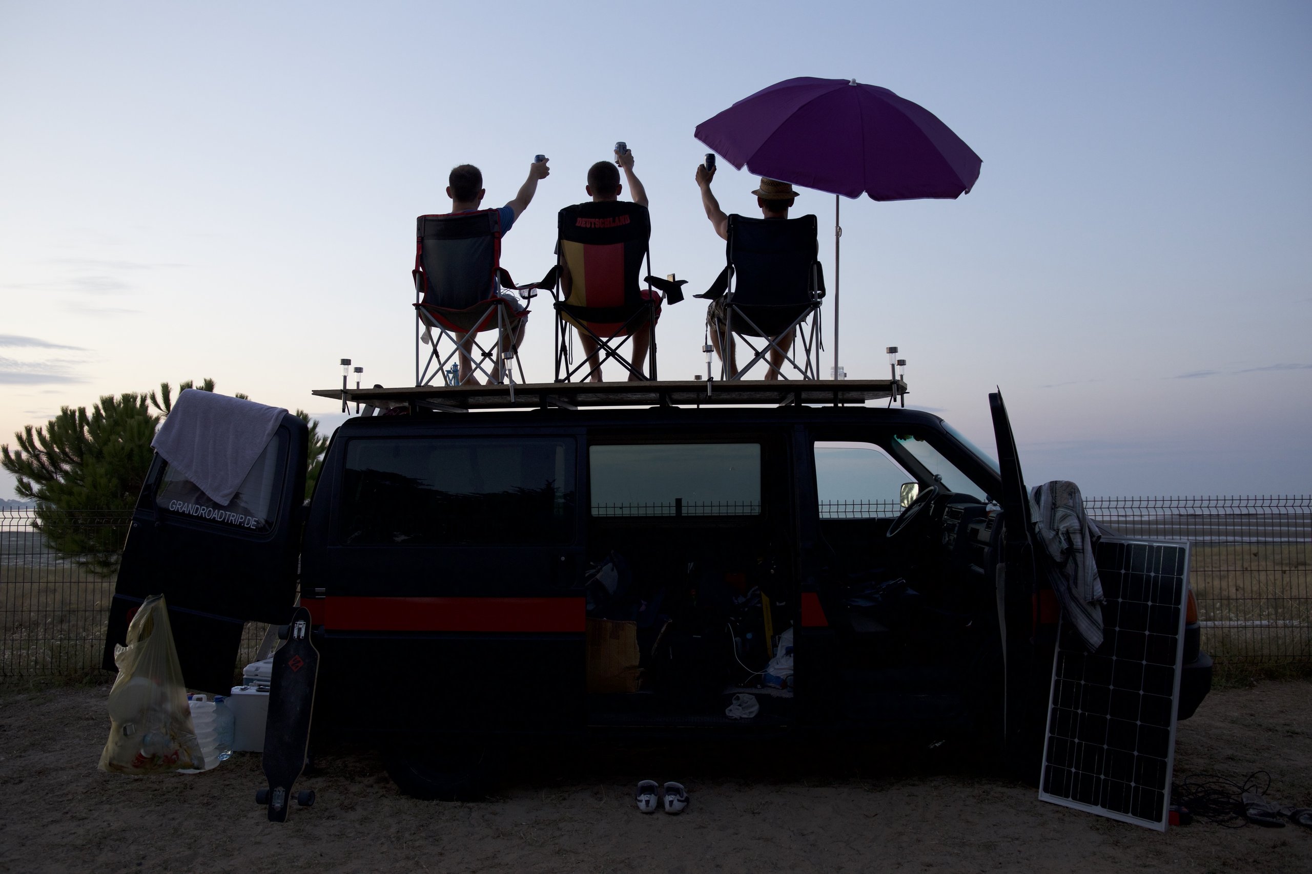 Der Bus von der Seite, auf dem Dach drei Campingstühle und ein Sonnenschirm