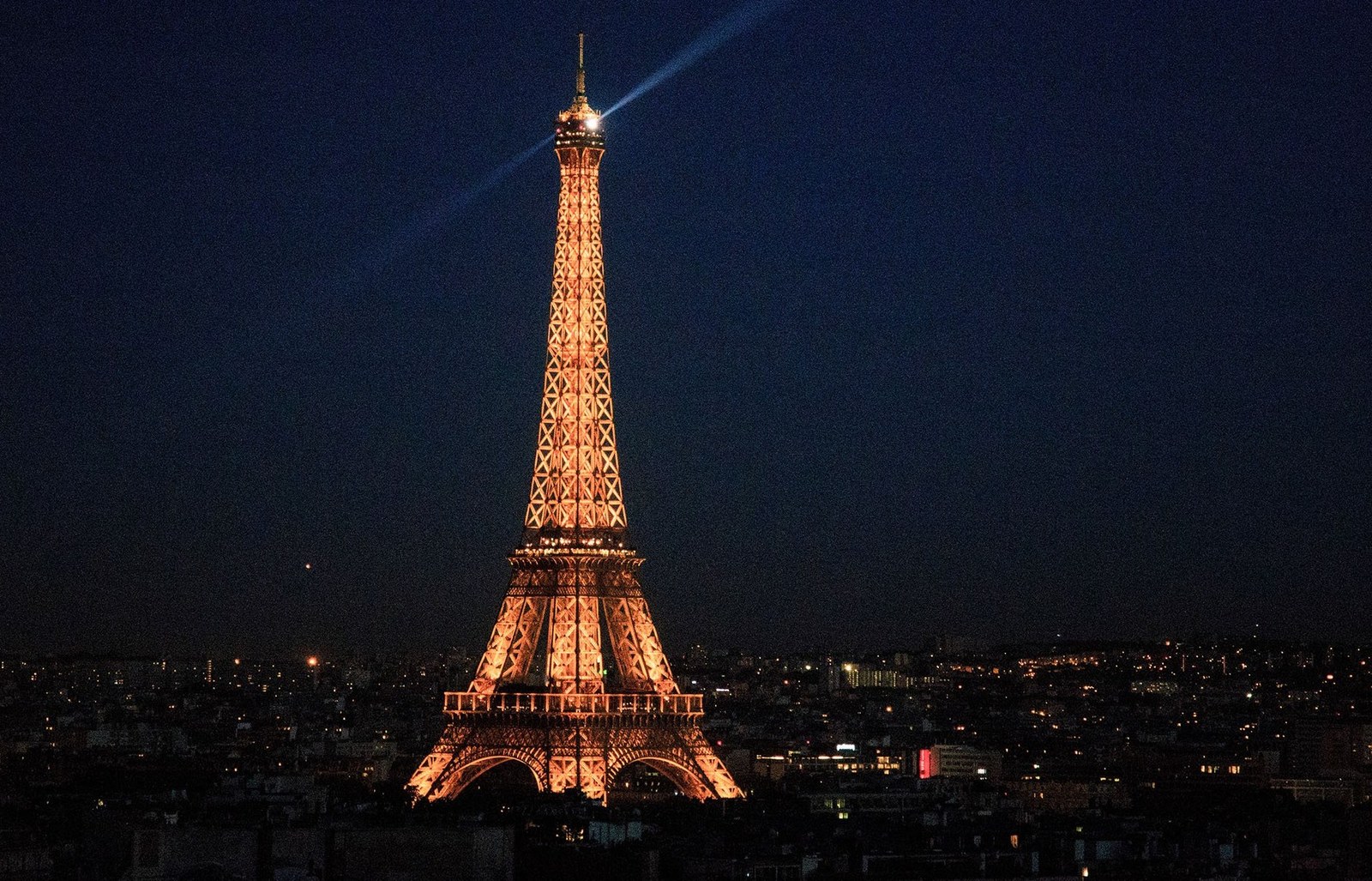 Der beleuchtete Eiffelturm bei Nacht über den Dächern von Paris